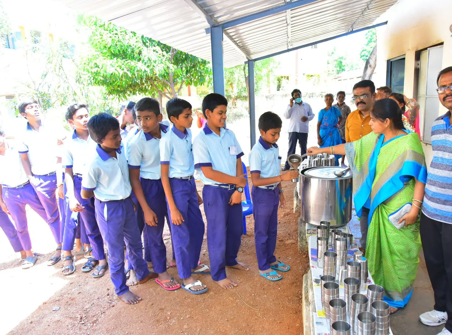 अपने विद्यालय में पौष्टिक रागी जावा के लिए कतार में खड़े स्कूली बच्चे