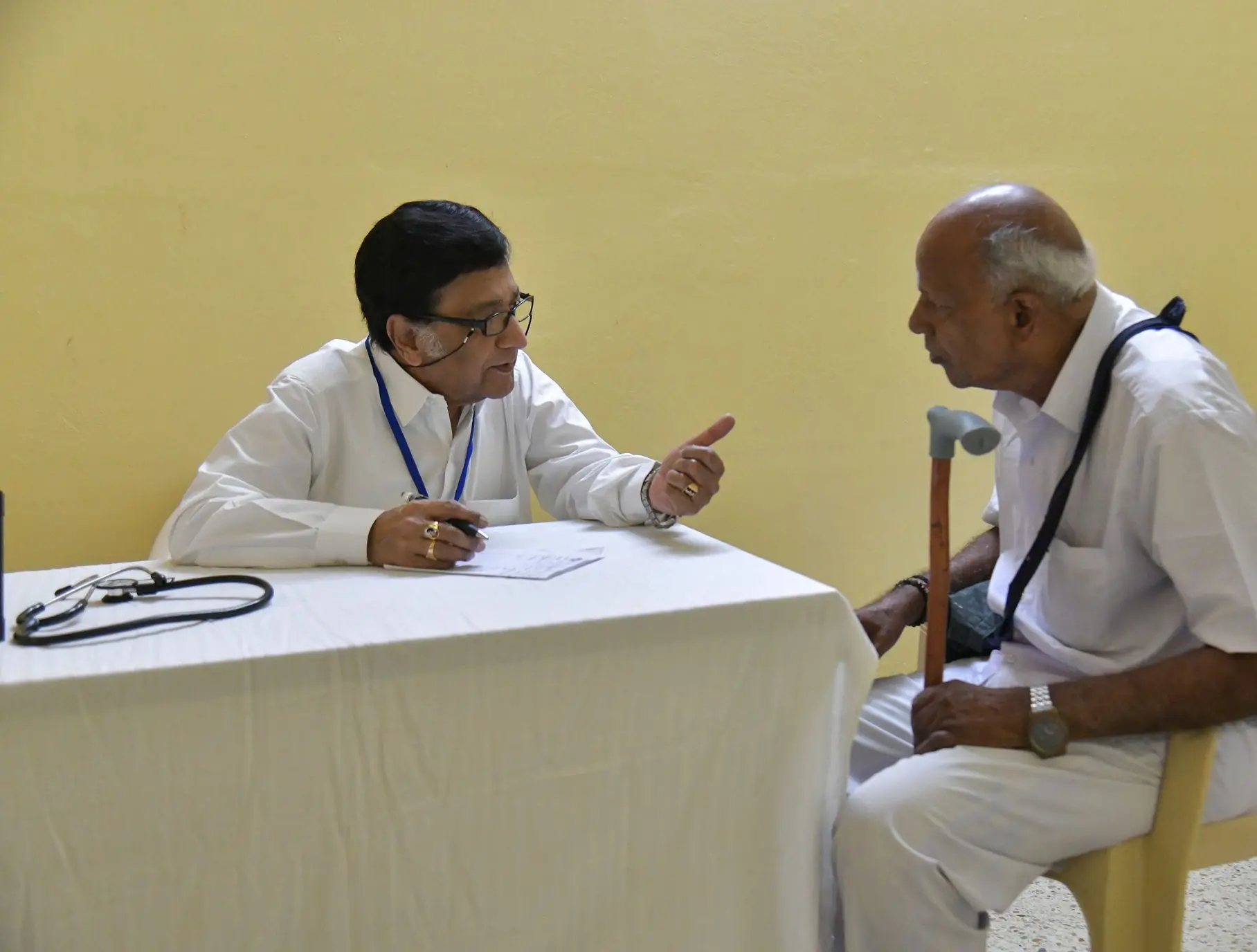 चिकित्सा शिविर में वृद्ध रोगी से परामर्श करते चिकित्सक